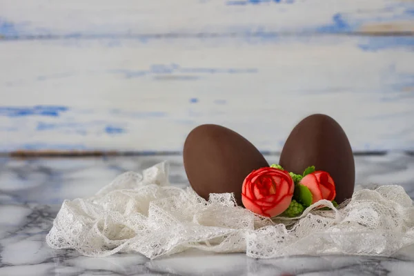 Шоколадные яйца, лента из белого кружева, искусственные декоративные розы — стоковое фото