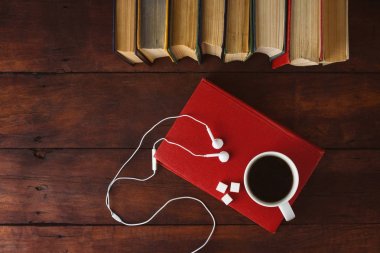 Kitap, beyaz kulaklık, kesme şeker ve beyaz fincan sıcak kahve ile