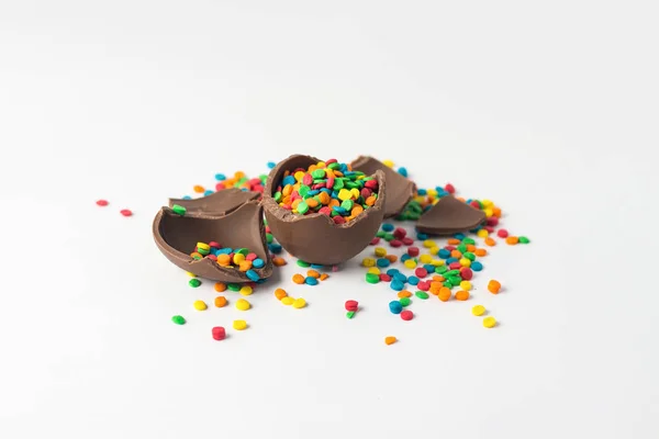 Broken Chocolate Easter egg with multi-colored candy decorations — Stock Photo, Image