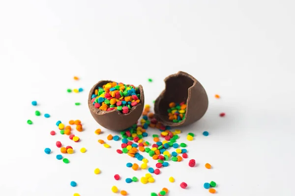 Broken Chocolate Easter egg with multi-colored candy decorations — Stock Photo, Image