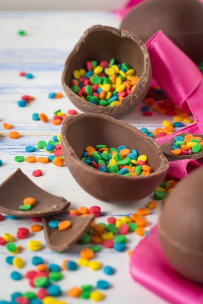 Пасхальные шоколадные яйца, розовая лента и разноцветные сладости на — стоковое фото