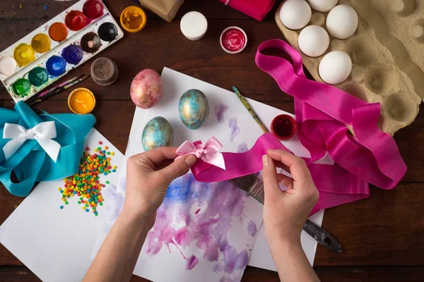 Female Hands at Time Painting Easter Eggs on a background of a d