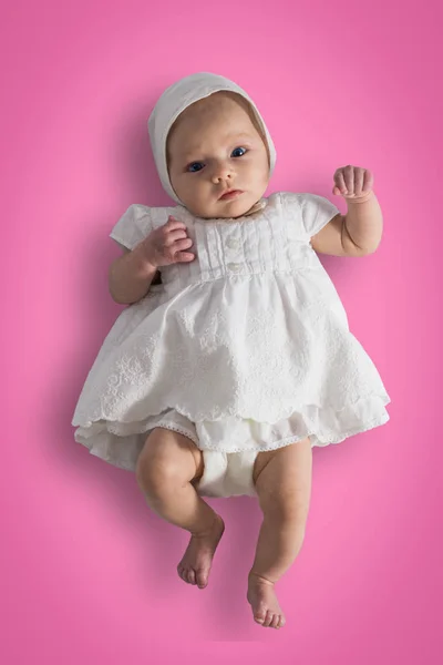 Pequena menina em vestido branco em comprimento total em um rosa claro b — Fotografia de Stock