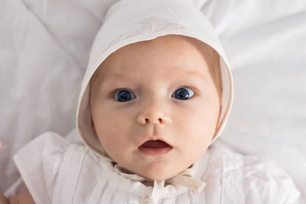 Маленькая девочка с голубыми глазами в белом платье и шляпу на белом — стоковое фото