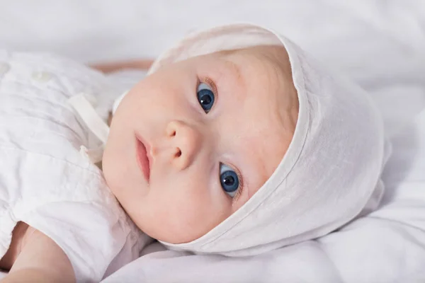 Маленькая девочка с голубыми глазами в белом платье и шляпу на белом — стоковое фото