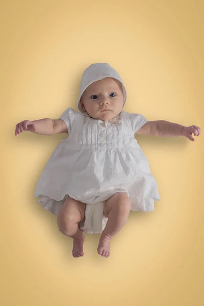 Pequena menina com olhos azuis em vestido branco e um boné em um ser — Fotografia de Stock