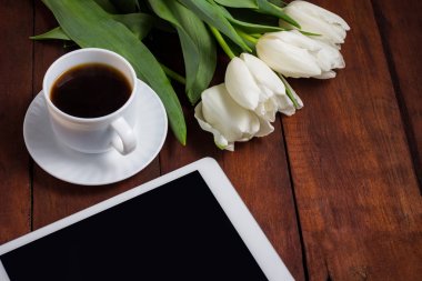 Beyaz Lale, bir fincan kahve ve koyu ahşap arka yüzündeki bir tablet