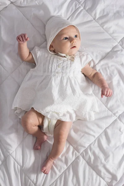 Pequena menina em vestido branco em comprimento total em um cobertor branco — Fotografia de Stock