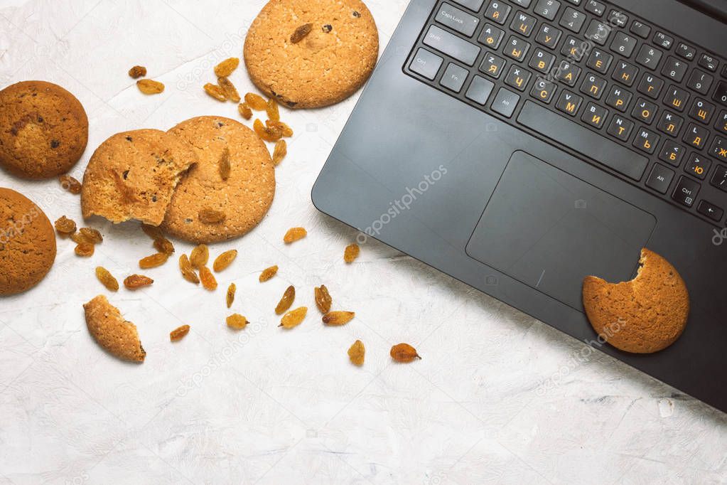 Homemade Oatmeal Cookies and Laptop on a Light Concrete Backgrou