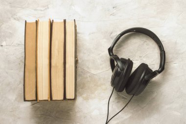 Kitap ve kulaklık beyaz taş zemin üzerine. Kavram Audiob