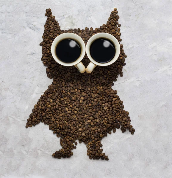 funny owl, made of coffee beans and two caps on stone background