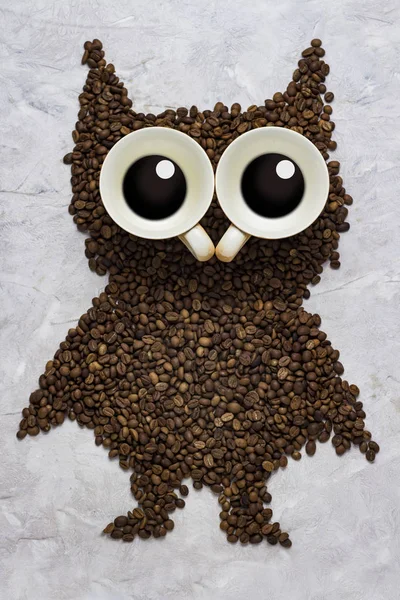 Смішна сова з обсмажених кавових зерен і дві чашки на кам'яному спині — стокове фото