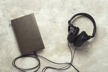 Kitap ve kendisine bir beyaz taş zemin üzerine bağlı kulaklık.