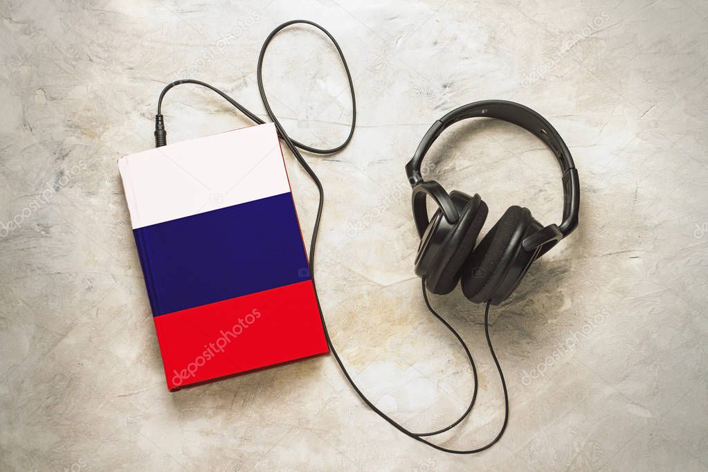 Headphones and book. The book has a cover in the form of a flag 