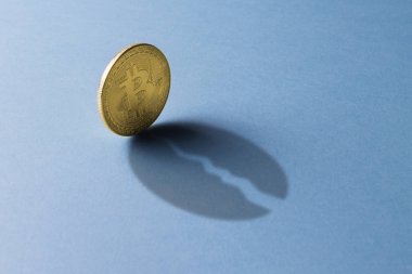 Bitcoin para bir gölge ile kırık bir sikke üzerinde mavi bir backgr yaprakları