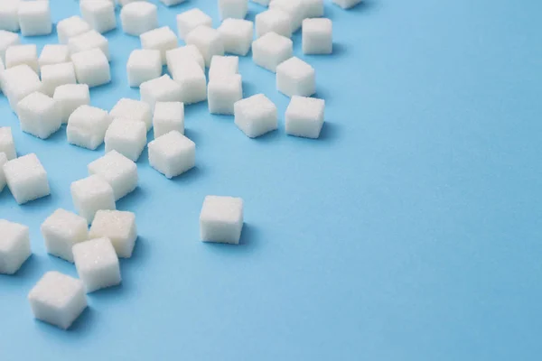 Muitos cubos de açúcar em um fundo azul . — Fotografia de Stock