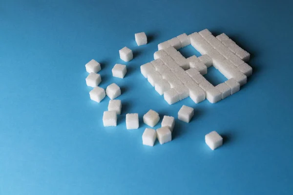 Crânio de cubos de açúcar e pedaços de açúcar em um fundo azul. T — Fotografia de Stock
