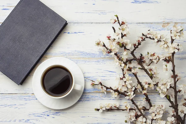 Sprig of cherries with flowers and white cup with black coffee a