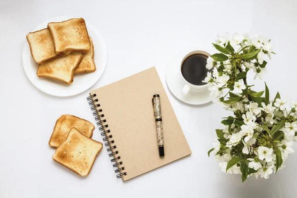 Cup with coffee, Toasts on a white plate, Notepad and a Branch w