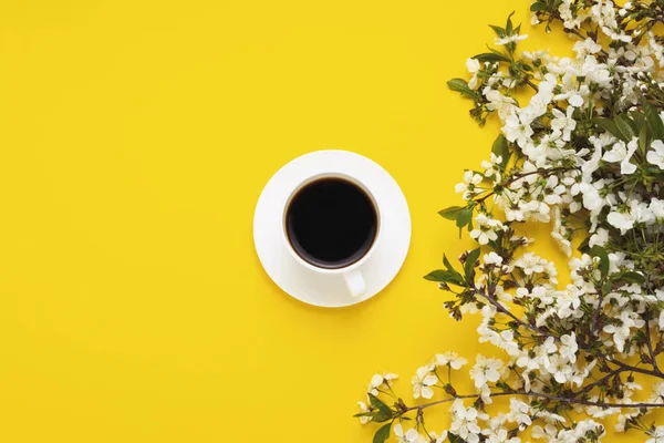 cup with black coffee, branches A cherry tree with white flowers