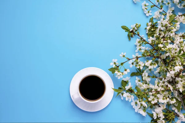 cup with black coffee, branches of a spring tree with white flow