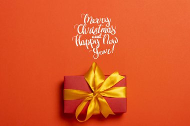 Kırmızı arka planda bir hediye kutusu. Mutlu Noeller mesajı ekledim. Tatil konsepti, Noel. Düz yatış, üst görünüm