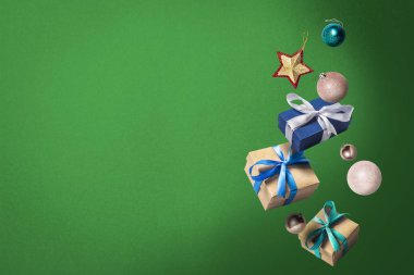Yeşil arka planda uçan hediye kutuları ve Noel süsleri. Tatil konsepti, Noel. Havalanma. Havadaki nesneler. Düz yatış, üst görünüm
