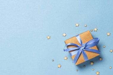 Dekoratif yıldızlı mavi arka planda mavi kurdeleli hediye kutusu. Sevilen biri için hediye konsepti, tatil. Düz yatak, üst manzara.