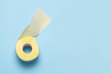 Mavi arka planda sarı tuvalet kağıdı rulosu. Kişisel hijyen konsepti. Düz yatış, üst görünüm
