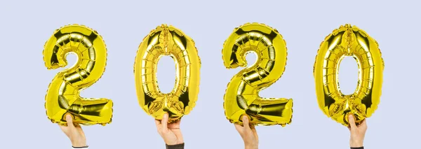 Manos sosteniendo globos de números 2020 sobre un fondo azul. Concepto año nuevo, el inicio de 2020, el año de la rata blanca. Banner — Foto de Stock