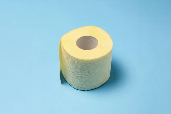 Rolo de papel higiênico amarelo em um fundo azul. Conceito de higiene pessoal. Deitado plano, vista superior — Fotografia de Stock