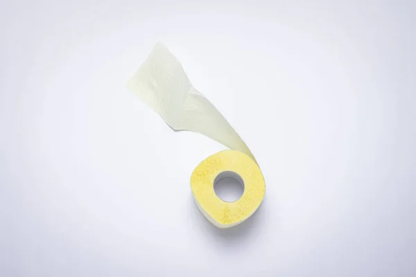 Rolo de papel higiênico amarelo sobre um fundo branco. Conceito de higiene pessoal. Deitado plano, vista superior — Fotografia de Stock