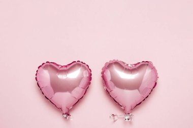 Pembe arka planda kalp şeklinde iki pembe hava balonu. Sevgililer Günü konsepti, düğün dekorasyonu. Folyo topları. Düz yatış, üst görünüm