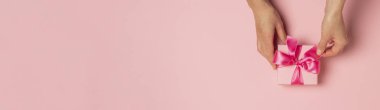 Dişi eller pembe arka planda bir hediye alır, alır, alır. Düğün konsepti, Sevgililer Günü, sevdiklerine bir hediye. Pankart. Düz yatış, üst görünüm