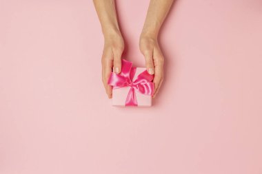 Dişi eller pembe arka planda bir hediye alır, alır, alır. Düğün konsepti, Sevgililer Günü, sevdiklerine bir hediye. Düz yatış, üst görünüm