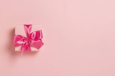 Pembe arka planda pembe kurdeleli pembe hediye kutusu. Düğün konsepti, Sevgililer Günü, sevdiklerine bir hediye. Pankart. Düz yatış, üst görünüm