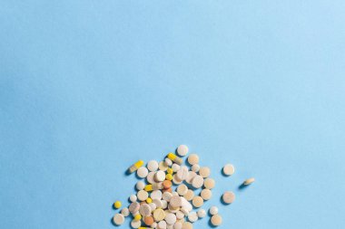 Mavi arka planda bir sürü farklı tipte hap var. Uykusuzluk, rejime göre haplar, vitaminler. Düz yatış, üst görünüm