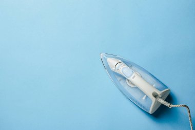 Bir şeyleri ütülemek için ütü ve mavi arka planda keten. Çamaşır konsepti, atölye. Düz yatış, üst görünüm