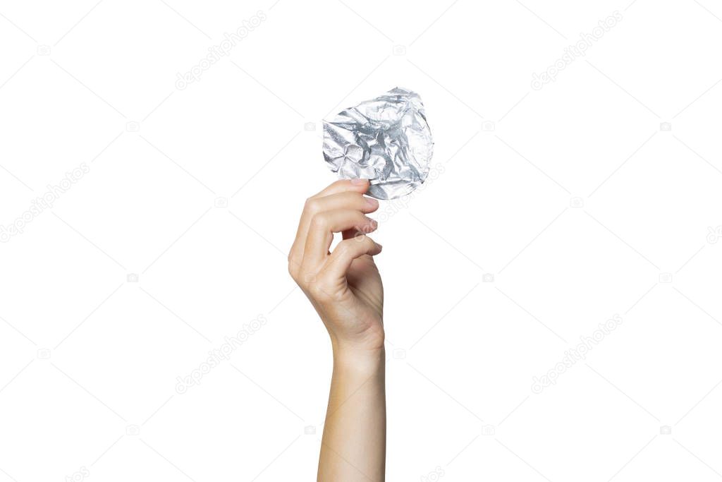 Female hand holds a crumpled foil lid on a white isolated background. The concept of separate trash, stop plastic, recycling