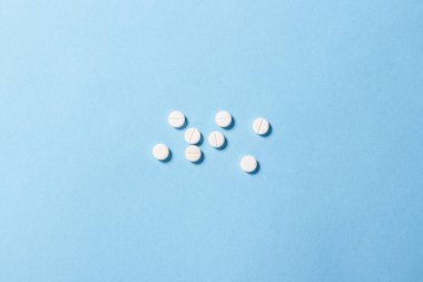Mavi arka planda beyaz haplar. Uykusuzluk, ilaç seçimi, vitaminler. Düz yatış, üst görünüm
