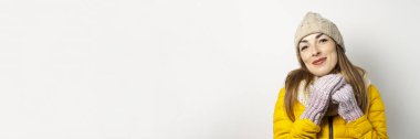 Genç bir kadın arka planda şapkasının altından dışarı bakıyor. Kış konsepti, kış modası, kış kıyafetleri. Komik ruh hali, duygular. Pankart