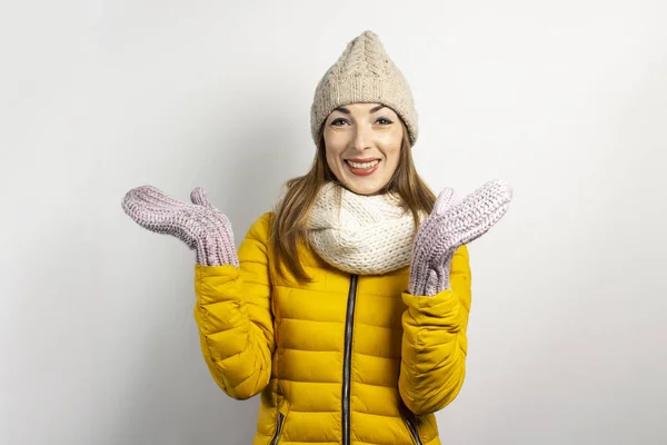 Femeia tânără cu o pălărie caldă și mănuși zâmbește pe un fundal ușor. Conceptul de iarnă, moda de iarnă, hainele de iarnă. Amuzant starea de spirit, emoții, surpriză, șoc — Fotografie, imagine de stoc