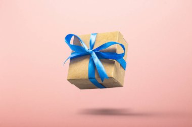 Pembe arka planda havada uçan bir hediye. Sevilen biri için hediye, doğum günü, Sevgililer Günü. Yükselme