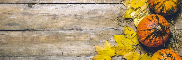 Citrouilles mûres, feuilles d'automne et paille sur fond de bois. Concept de récolte, automne, veille d'Halloween. Bannière. Couché plat, vue du dessus — Photo