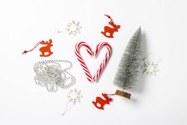 Kalp şeklinde şeker kamışı, dekoratif Noel ağacı, beyaz arka planda süslemeler. Noel 'i, yeni yılı, minimalizmi düşün. Düz yatış, üst görünüm