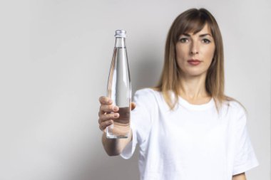 Genç bir kadın arka planda temiz su dolu bir şişe tutuyor. Pankart. Susuzluk, sıcaklık, sağlık ve güzellik konsepti, su dengesi.