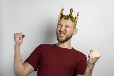 Kafasında taç olan genç adam seviniyor ya da arka planda bir şeyleri kutluyor. Kavram, kral, şans, kazanç, zenginlik, hayal, amaç, istektir. Pankart