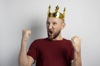 Kafasında taç olan genç adam seviniyor ya da arka planda bir şeyleri kutluyor. Kavram, kral, şans, kazanç, zenginlik, hayal, amaç, istektir. Pankart