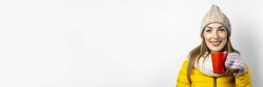 Sarı ceketli ve şapkalı genç bir kadın arka planda bir bardak kahve ya da çay tutuyor. Duygusal kahkaha, sürpriz, öpücük. Kışı, sonbaharı, kahvehaneyi düşün. Pankart