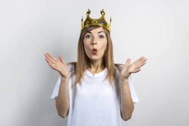 Kafasında taç olan genç bir kadın ve hafif bir arka planda şaşırmış bir yüz. Duygusal kahkaha, sürpriz, öpücük, şok. Kraliçe konsepti, şans, en iyisi, kazanmak, zafer. Pankart